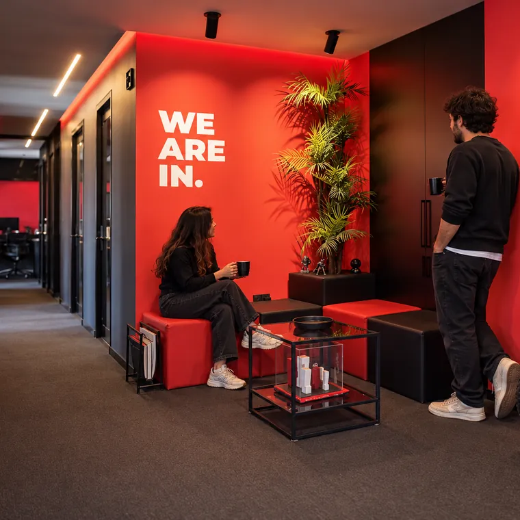 Colleagues chatting by the WE ARE IN wall